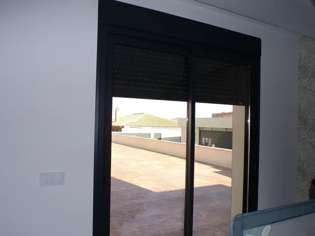 Ventana corredera de aluminio negro con persiana, vista desde el interior