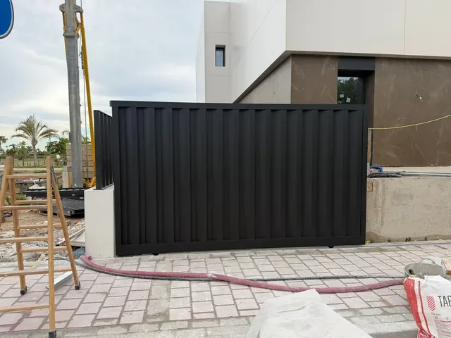 Puerta corredera de lamas verticales negras para acceso de parcela